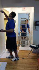 Two Dannible & McKee employees painting the inside of a room and hallway