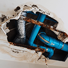 Hole in ceiling with exposed blue pipes