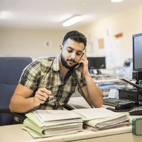 Man working on files and talking on the phone in office