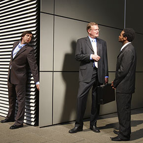Business man eavesdropping on 2 business men talking