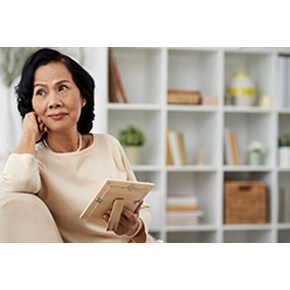 Woman thinking with picture on couch and bookcases in the background