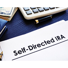 Self-directed IRA written on a white paper and partial view of money and calculator