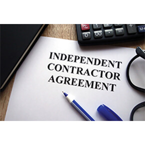 Contractor agreement paperwork written on white paper with partial pen, calculator and glasses
