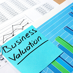 Business Validation blue sticky note on top of papers with charts on them