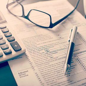 Individual income tax return form, glasses, pen and calculator on desk