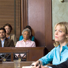 Woman sitting in courtroom with part of jury in background