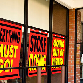 Store windows with signs that say store closing, going out of business,, and everything must go