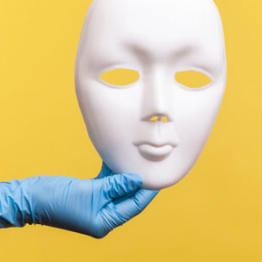 Medical glove holding white full face mask