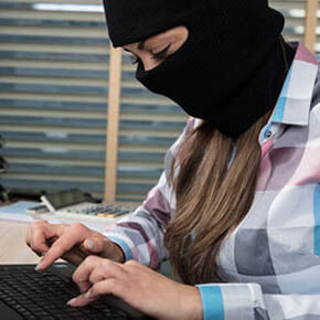 Woman wearing ski mask cyberattacking computer