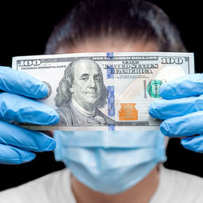 Person wearing face mask and gloves holding $100 bill in front of their face - covering their identity