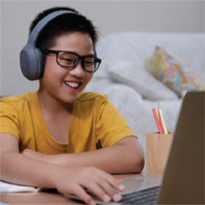 Boy using laptop computer with headphones on