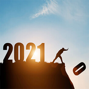 Man pushing the number zero off cliff with the numbers 2021 behind him with sun in background