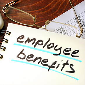Employee benefits written on a notepad with a pair of glasses lying next to the notepad