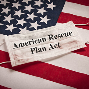 Protective medical mask on the background of the American flag and the caption of American Rescue Plan Act on the mask.