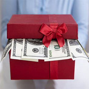 A red gift box slightly open with cash coming out of it