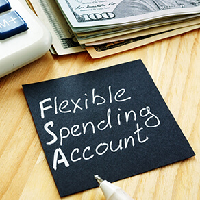 Black post it with the words "Flexible Spending Account" written on it resting on a desk