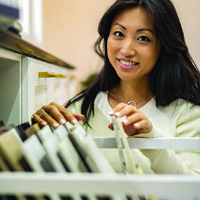 Young woman smiling as she goes through a file drawer in an office