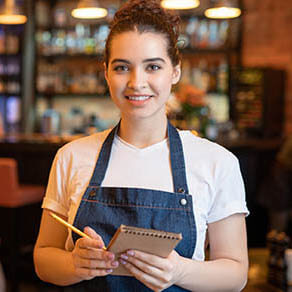 Young smiling waitress in workwear standing in luxurious restaurant