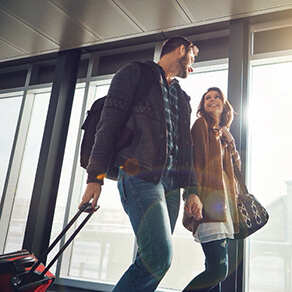 Man and woman walking through airport pulling luggage