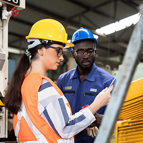 African American male and female industrial engineering in safety uniform, hard hats working and discussing in the heavy industry manufacturing factory