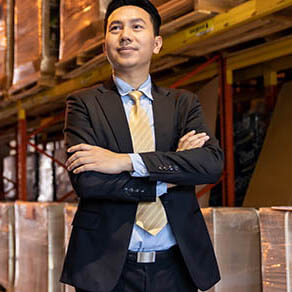 Portrait of confidence businessman investor stand in large factory and distribution warehouse environment. Business owner and investment concept.