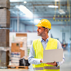 Warehouse manager with laptop entering inventory data to database