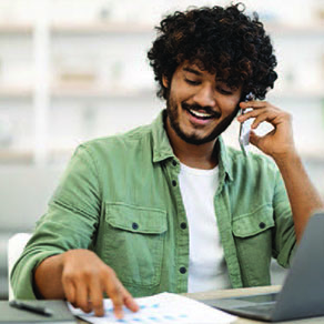 Young man on phone; smiling and looking at graphs.