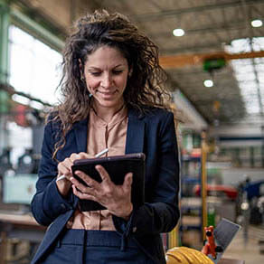 Portrait of female chief engineer in modern industrial factory using tablet.