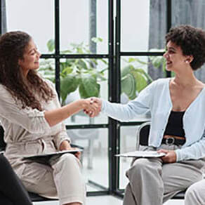 Two women shaking hands in a casual business meeting