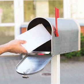 A close up of someone's hand putting mail into a mailbox