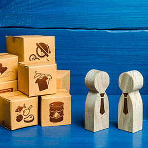 People figurines "conducting business negotiations" next to wooden boxes with printed images of trade goods and services