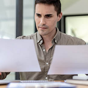 A business man holding and looking at two documents