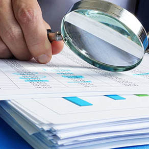 Auditor is working with financial documents with a magnified glass.